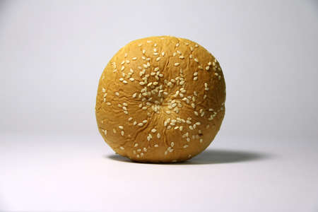 Bread with white sesame seeds on white background. it is a food made of flour, water, and yeast or another leavening agent, mixed together and baked.の写真素材