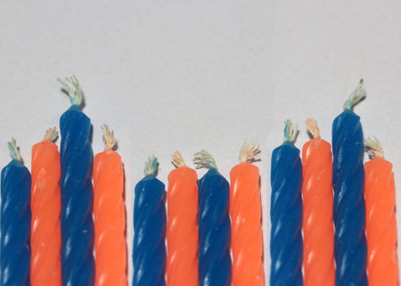 Birthday candles, blue and orange color on white background. a cylinder or block of wax or tallow...