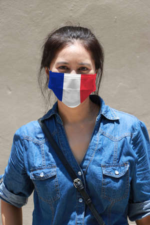 France flag on hygienic mask. Masked Asian woman prevent germs and wear denim skirt dress. concept of Tiny Particle protection or virus corona or Covid 19.の写真素材
