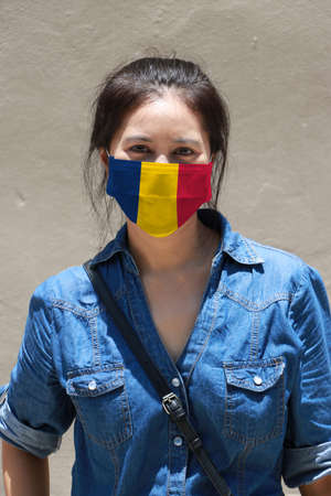 Chad flag on hygienic mask. Masked woman prevent germs and wear denim dress. Tiny Particle or respiratory disease protection. Concept of Combating illness.の写真素材