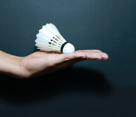 A badminton ball is placed on supine palm with dark background.の写真素材