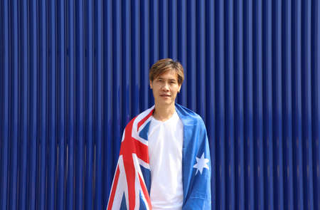 The man in white shirt with Australia flag on his shoulder on blue background.の写真素材
