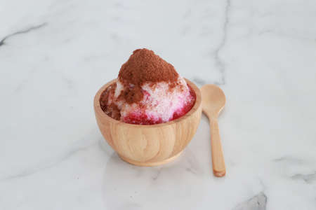 crushed ice Or shaved ice with sweet red water and sweetened condensed milk, Topped with chocolate powder, looks like a volcano. in a round wooden bowl with wooden spoon. It is a dessert that is refreshing to eat. wooden spoon. It is a dessert that is refreshing to eat.の写真素材