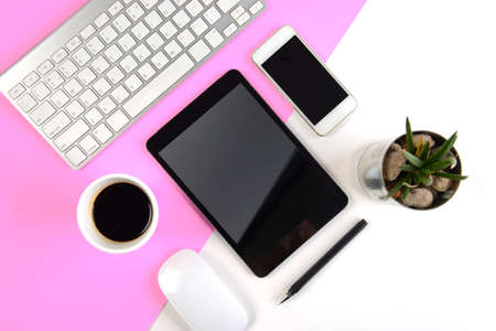 Office table with  keyboard, mouse, notebook, digital tablet and smartphone on modern two tone (white and pink) background.の写真素材