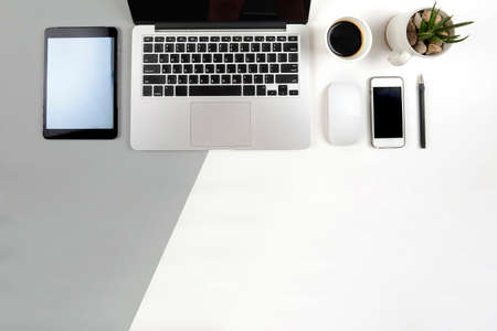 Office table with  laptop computer, notebook, digital tablet and smartphone on modern two tone (white and grey) background.の写真素材
