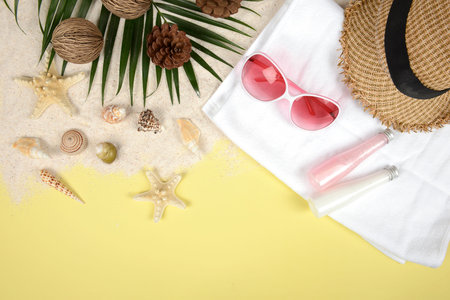 Summer concept and accessories(shells, starfish, coconut leaf)with sandy beach on yellow background.