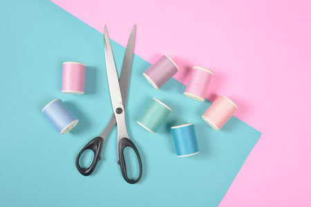 Flat lay of colored thread rolls and Scissors for sewing on two tone background, Sewing and needlework concept.の写真素材