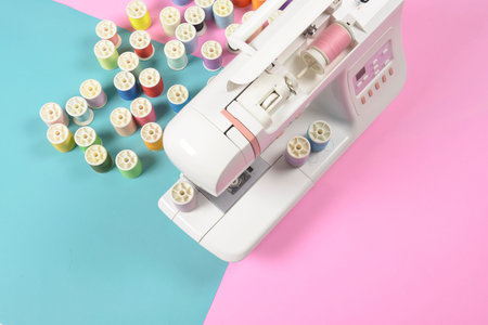 Sewing machine and colorful thread rolls for sewing on two tone background, Sewing and needlework...