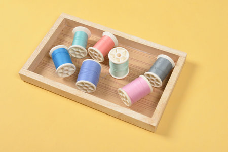 Flat lay of colored thread rolls for sewing on yellow background, Sewing and needlework concept.