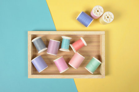 Flat lay of colored thread rolls for sewing on two tone background, Sewing and needlework concept.