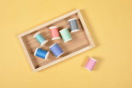 Flat lay of colored thread rolls for sewing on yellow background, Sewing and needlework concept.の写真素材