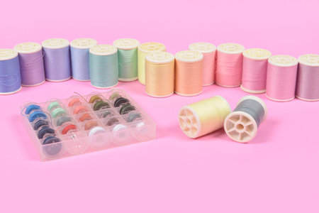 Flat lay of colored thread rolls for sewing on pink background, Sewing and needlework concept.