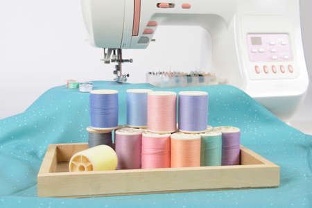 Sewing machine and colorful thread rolls, scissors, fabric and accessories for sewing on white background, Sewing and needlework concept. (Selective Focus)の写真素材