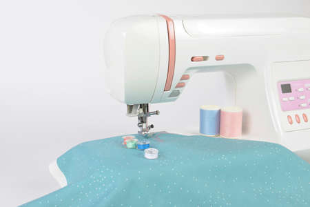 Sewing machine and colorful thread rolls, scissors, fabric and accessories for sewing on white background, Sewing and needlework concept. (Selective Focus)の写真素材