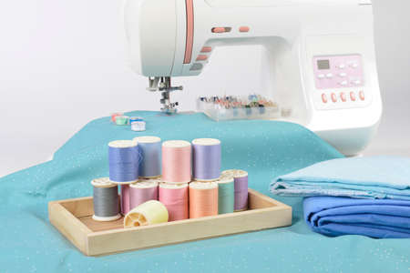 Sewing machine and colorful thread rolls, scissors, fabric and accessories for sewing on white background, Sewing and needlework concept. (Selective Focus)の写真素材