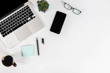 Office table with laptop computer, smartphone, pen, notebook and coffee on isolated pure white background / Laptop and tablet mockup concept. (Selective Focus)の写真素材