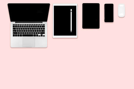 Flat lay photo of office table with laptop computer, digital tablet, mobile phone and accessories. on modern pink tone background. Desktop office mockup concept.の写真素材