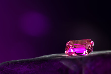 Ruby gemstone on a black background with purple bokeh.