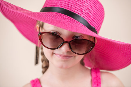 Portrait of a cute little girl wearing a pink hat and sunglassesの写真素材
