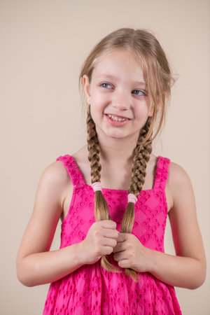 Portrait of a little girl with braids on a beige backgroundの写真素材