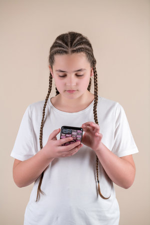 Portrait of a teenage girl with braids using mobile phone.の写真素材