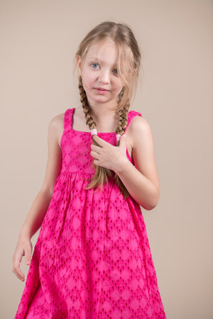 Portrait of a little girl in a pink dress on a beige backgroundの写真素材
