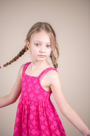 Portrait of a beautiful little girl with braids in a pink dressの写真素材