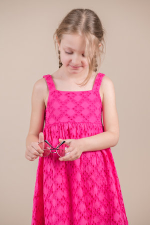 Little girl in a pink dress holding a pair of scissors in her handsの写真素材