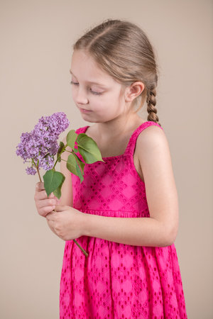 Little girl with a bouquet of lilacs on a beige backgroundの写真素材