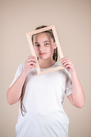 Portrait of a cute little girl holding a picture frame on gray backgroundの写真素材