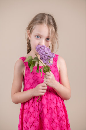 Little girl with a bouquet of lilacs on a beige backgroundの写真素材