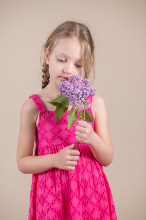 Little girl in a pink dress with a bouquet of lilacsの写真素材