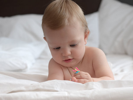 Cute baby boy playing with colorful toy on the bed at homeの写真素材