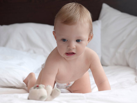 Cute little baby playing on bed at home, focus on eyesの写真素材