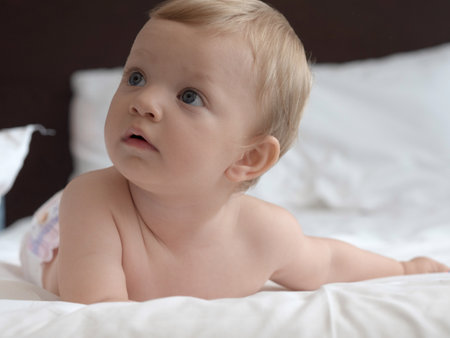 Portrait of adorable baby lying on bed at home, closeupの写真素材