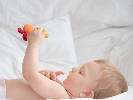 Cute little baby playing with toy on bed at home, closeupの写真素材