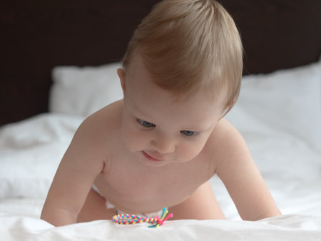 Cute baby boy playing with colorful toy on the bed at homeの写真素材