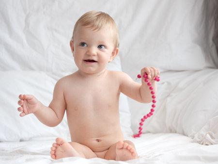 Portrait of cute baby boy with beads on bed at home.の写真素材
