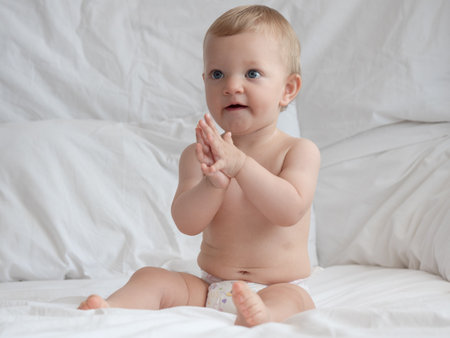 Portrait of cute baby boy with blue eyes on white bed.の写真素材