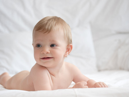 Cute little baby lying on white bed at home, closeupの写真素材