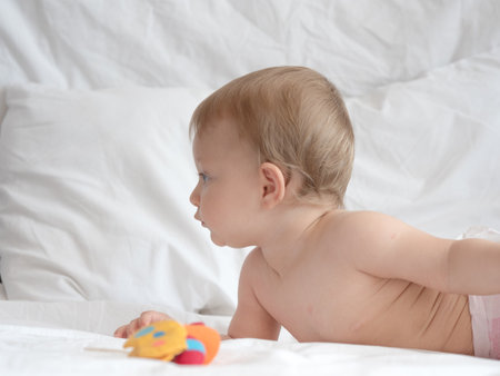 Cute little baby playing with toy on bed at home, closeupの写真素材