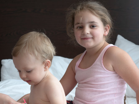 Two cute little girls playing on the bed in the bedroom. Kids play together.の写真素材