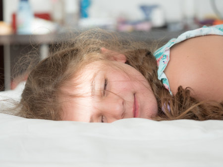Portrait of a cute little girl sleeping on the bed at homeの写真素材
