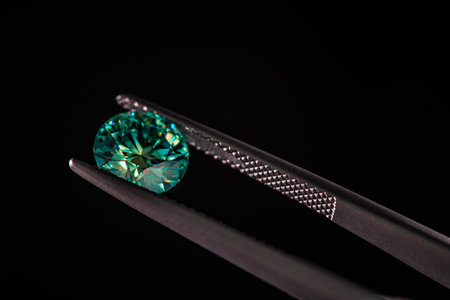 jewelry tweezers with emerald on a black backgroundの写真素材