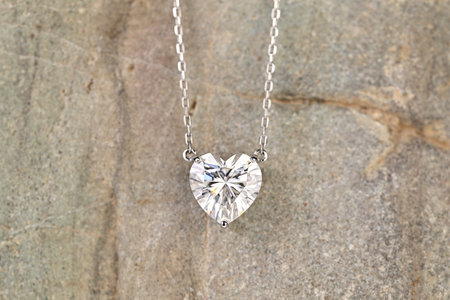 A heart shaped pendant with a diamond in the center. The pendant is hanging from a chainの写真素材