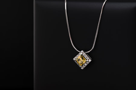 A blue and white necklace sits on a black surface. The necklace is made of silver and has a diamond pendant. The necklace is simple and elegant, with a modern designの写真素材