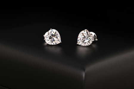 A pair of earrings with a diamond in the center. The earrings are sitting on a black surfaceの写真素材