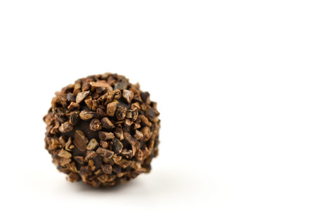 A chocolate covered ball with a lot of brown pieces on it. The texture of the chocolate is rough and...