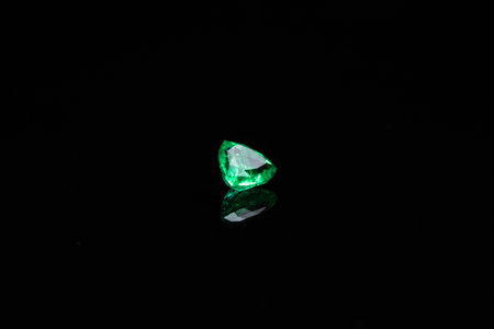 A green gemstone is on a black background. The gemstone is shiny and has a green colorの写真素材