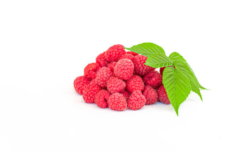 A bunch of red raspberries with a leaf on top. The raspberries are fresh and ripe, and the leaf adds a touch of greenery to the sceneの写真素材